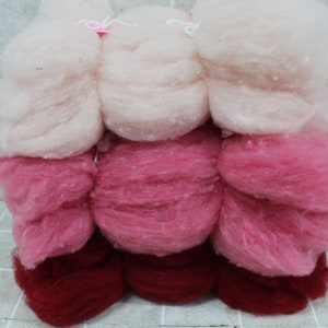 May include: Three balls of yarn in shades of pink and red. The top ball is a light pink, the middle ball is a darker pink, and the bottom ball is a deep red.