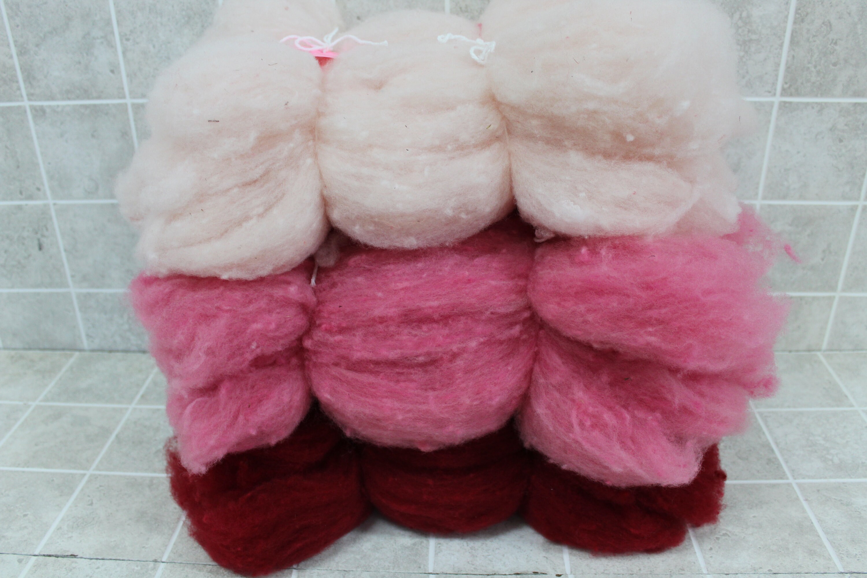 Wool- reds or pinks in 4-ounce bundles. 4 one-ounce batts of carded Corriedale wool for needle and wet felting and other crafts