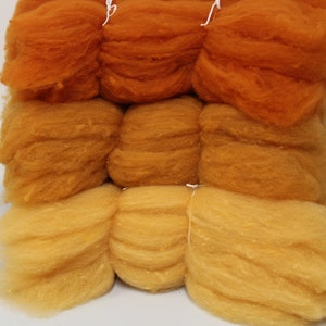 May include: Three stacks of orange, yellow, and light yellow wool roving. The wool is soft and fluffy, and it is perfect for felting or spinning.