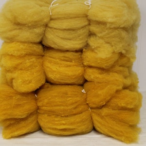 May include: A stack of yellow wool roving, a type of fiber used for spinning yarn or felting.