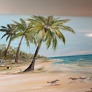 May include: Hand-painted artwork showing a tropical beach scene. The artwork features palm trees, a sandy beach, and the ocean under a blue sky. Several birds are walking on the sand. The colour palette includes shades of green, blue, and tan.