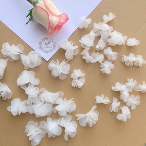 Peut inclure: Une collection de fleurs en tissu blanc, parfaites pour ajouter une touche d'élégance à vos projets de bricolage.