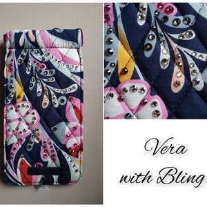 May include: A navy blue quilted phone case with a colorful floral pattern and rhinestones. The case has a Vera Bradley logo.