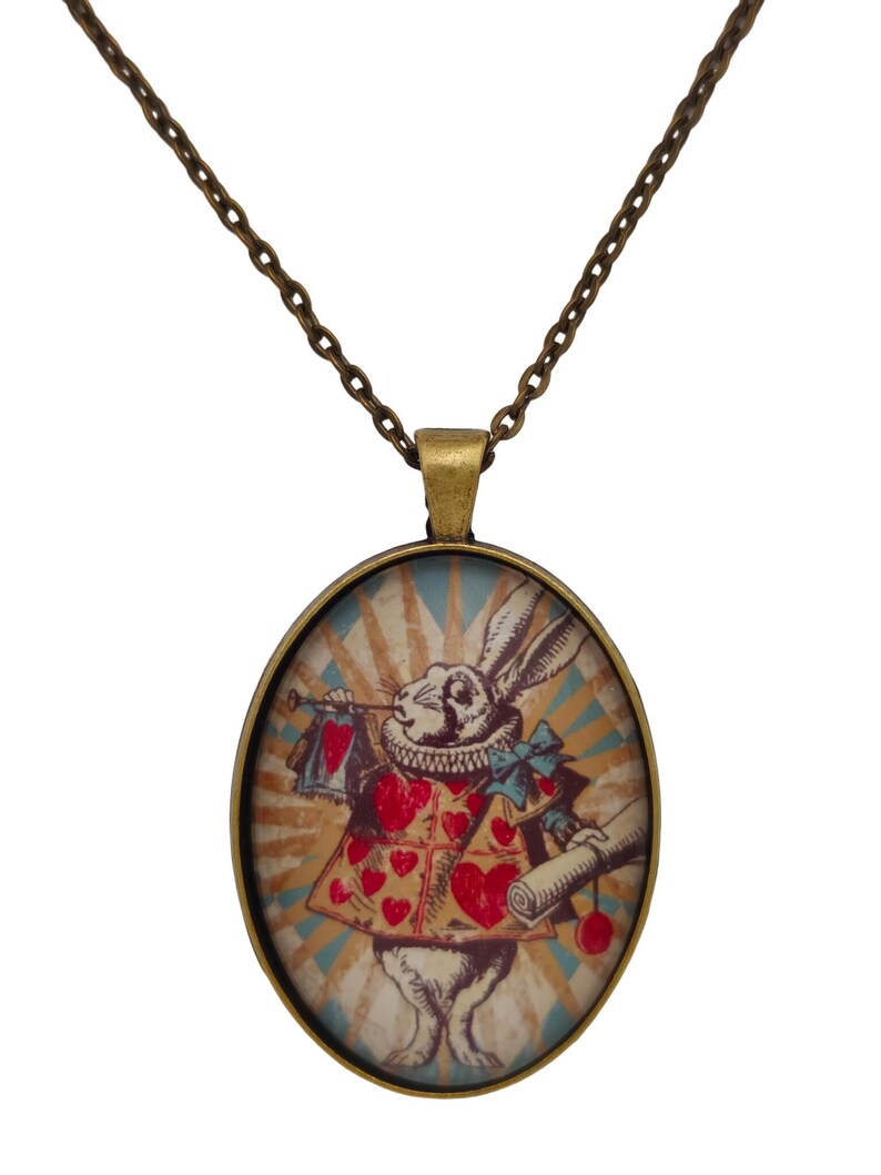 May include: A bronze chain necklace with an oval pendant featuring a vintage illustration of the White Rabbit from Alice in Wonderland. The rabbit is wearing a red and white suit with a heart pattern and holding a pocket watch and a scroll.