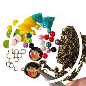 May include: A close-up of a necklace with a cat charm, beads, and a pair of pliers. The necklace is made of a gold chain and the charm is a round glass cabochon with a picture of a cat. The beads are a variety of colours, including red, green, blue, and white.