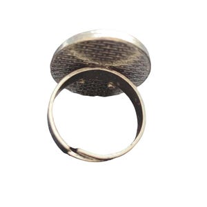 May include: Adjustable silver ring with a round, textured, silver-toned top.