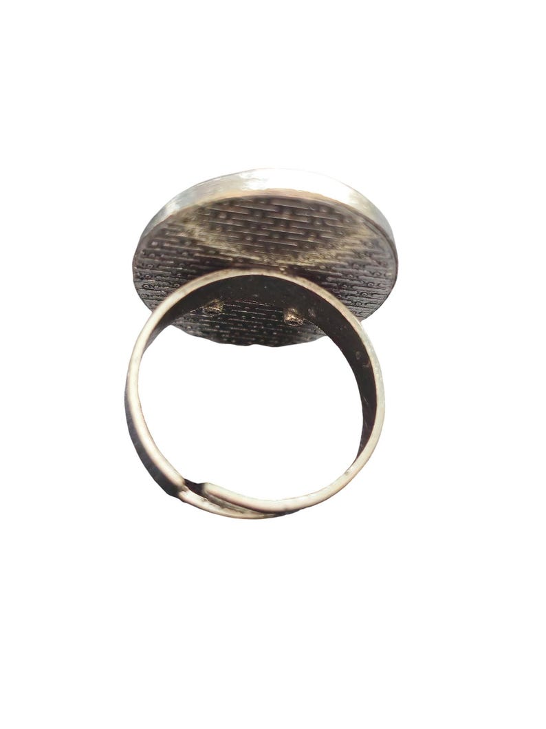 May include: Adjustable silver ring with a round, textured, silver-toned top.