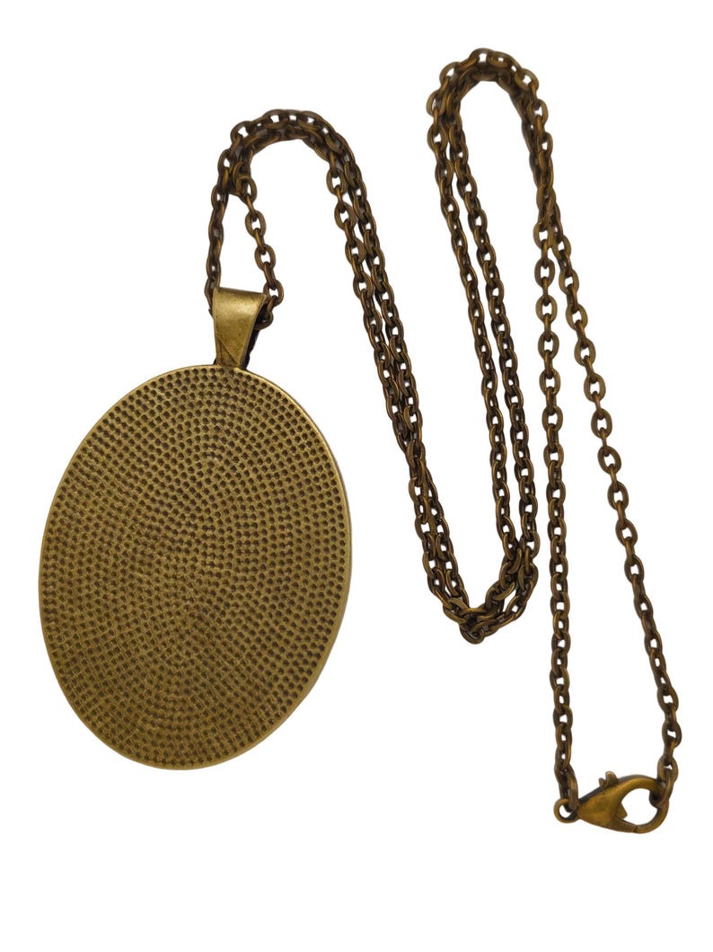 May include: A gold-toned chain necklace with a round pendant. The pendant has a textured surface and a smooth, polished edge.