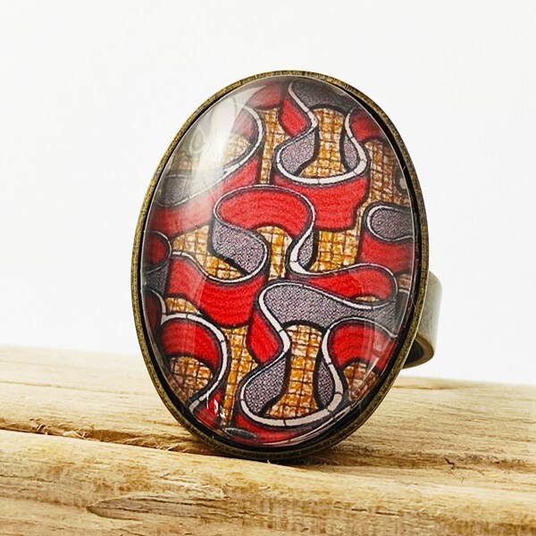 Bague adaptable. Métal couleur bronze. Cabochon ovale en verre.  WAX. Motifs africains.