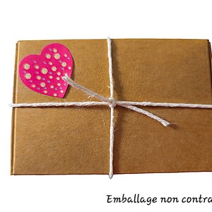 May include: A brown cardboard box tied with white twine and decorated with a pink heart sticker with white polka dots.