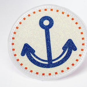 Könnte beinhalten: Ein runder, weißer Stoff-Patch mit einem blauen Anker-Design. Der Anker hat einen weißen Umriss und ist von einem roten und weißen gepunkteten Rand umgeben.
