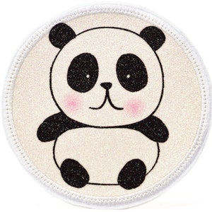 Könnte beinhalten: Ein runder, weißer, glitzernder Patch mit einem weißen, gestickten Rand. Auf dem Patch ist ein schwarz-weißes Panda-Bärchen mit rosa Wangen abgebildet.