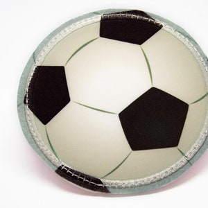 Könnte beinhalten: Ein weiß-schwarzer Fußball-Patch mit einem hellblauen Rand. Der Patch ist an den Rändern vernäht.
