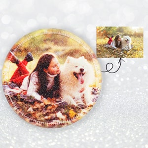 Könnte beinhalten: Runder, glitzernder Untersetzer mit einem Foto eines Mädchens und eines flauschigen weißen Hundes in Herbstblättern. Der Untersetzer hat einen genähten Rand und ein kleineres eingesetztes Bild derselben Szene.
