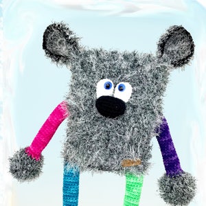 May include: A gray crocheted stuffed animal with blue eyes and a black nose. The animal has long, colorful crocheted legs with pom-poms at the ends. The animal is standing on a light blue background. The text "kuschelschnuffelbande...hakeln und lieb haben" is at the bottom of the image.