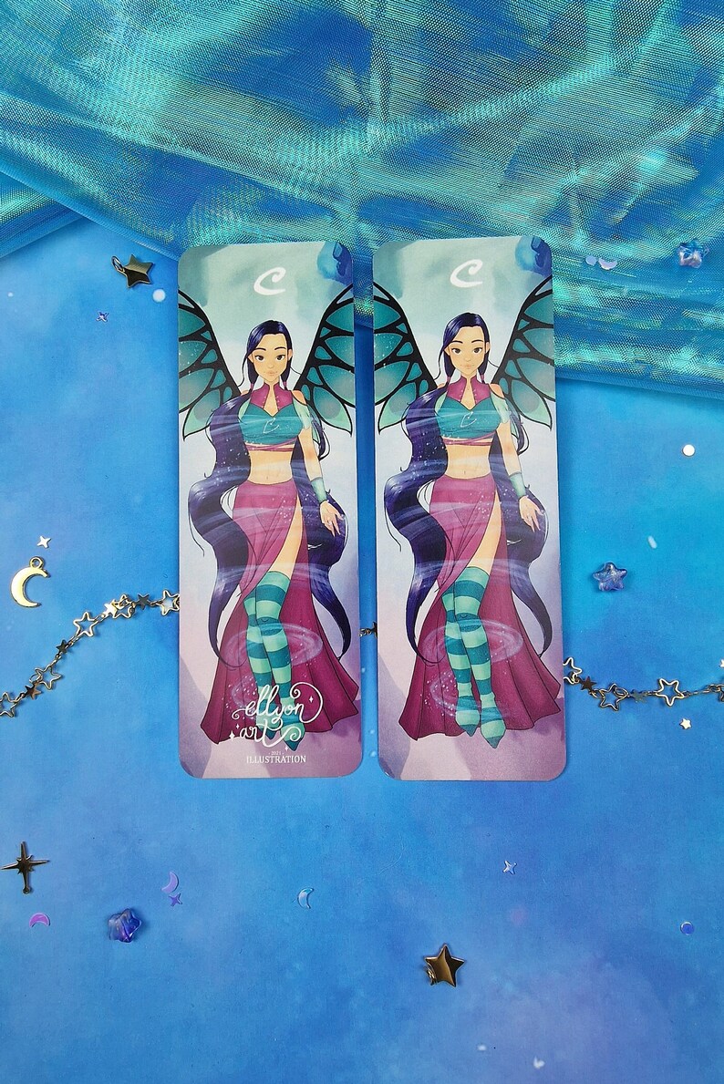 May include: Two colourful bookmarks featuring a cartoon illustration of a female character with blue hair, wings, and a pink and green outfit. The text "ellyon art" and "ILLUSTRATION" are printed on the bottom of the bookmarks.