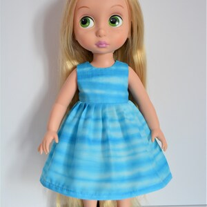 May include: A doll with long blonde hair wearing a blue and white striped dress and blue shoes.