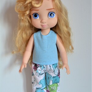Puede incluir: Una mu&ntilde;eca con el pelo largo y rizado rubio que lleva una camiseta azul claro sin mangas con una falda estampada en blanco y azul. La mu&ntilde;eca tiene ojos azules y una boca rosa p&aacute;lida.