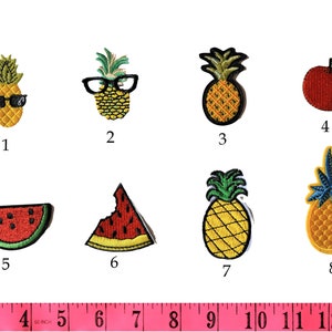 May include: A selection of embroidered fruit patches. Designs include pineapples, an apple, and watermelon slices. The patches are roughly 2.5 to 5 cm in size, with bright colours and detailed stitching. A pink measuring tape is at the bottom.