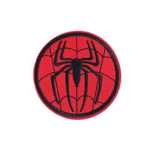 May include: Round, red patch featuring a black spider web design with a black spider in the center. The patch has a black border. This patch is suitable for clothing, bags, or other fabric items.
