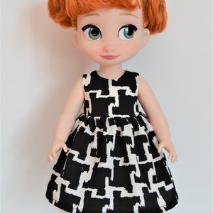 May include: A red-haired doll wearing a black and white geometric print dress and black shoes with a green flower detail.