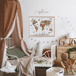 May include: A white bed frame with a brown canopy and a green blanket. A world map poster with the text "mini explorers" is hanging on the wall above the bed. The wall is decorated with beige star stickers.