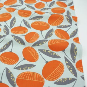 Puede incluir: Una tela azul claro con un patrón repetido de flores estilizadas de color naranja y hojas grises. Las flores tienen un diseño segmentado y las hojas tienen pequeños puntos amarillos.
