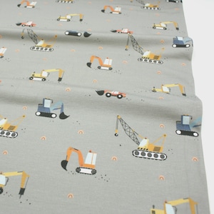 May include: Gray fabric with a repeating pattern of colorful construction vehicles, including excavators, cranes, and dump trucks. The design also features small orange rainbows. The vehicles are in shades of orange, yellow, blue, and red.