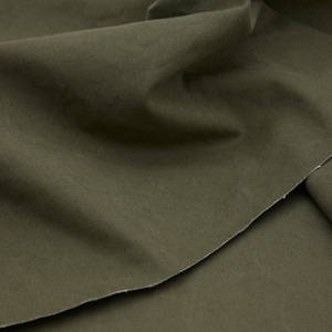 Könnte beinhalten: Nahaufnahme eines gefalteten Stücks dunkelgrünen Stoffes. Der Stoff hat eine glatte, gleichmäßige Textur und einen dezenten Glanz.