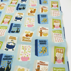 Könnte beinhalten: Hellblauer Stoff mit einem sich wiederholenden Muster aus Cartoon-Müsli-Schachteln. Die Schachteln tragen Namen wie "Honey Homies" und "Banana Buddies". Jede Schachtel hat ein einzigartiges Design und Farbschema.