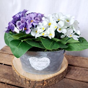 Artificial African violets in a rustic tin