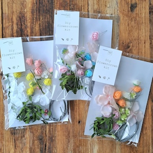 May include: Three clear plastic bags containing DIY flower crown kits. Each bag contains a variety of artificial flowers, leaves, and wire. The bags are labeled "DIY flowercrown kit".