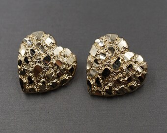 May include: A pair of gold heart-shaped earrings with a textured, diamond-cut finish.