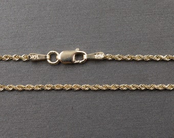 May include: A gold rope chain necklace with a lobster clasp. The chain is marked "10K" on the clasp.