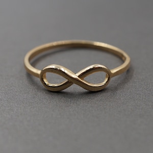 May include: A gold infinity symbol ring. The ring is simple and elegant, with a smooth finish.