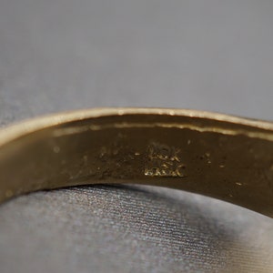 May include: Close-up of the inside of a gold band ring with the inscription "14K" and "Italy" visible.