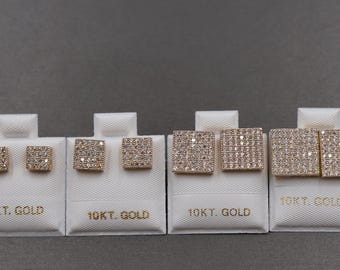 May include: Four pairs of square-shaped stud earrings on white display cards. The earrings are gold-toned and encrusted with small, sparkling stones. The cards are labeled "10KT. GOLD" in gold lettering, set against a gray background.