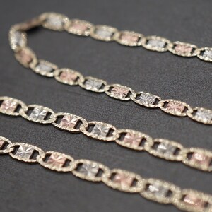 May include: A gold chain necklace with three-toned links. The links are a mix of yellow, white, and rose gold.