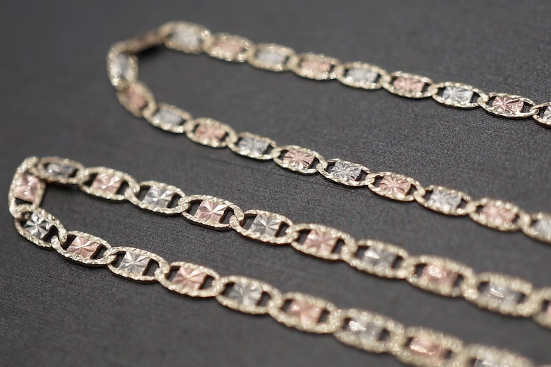 May include: A gold chain necklace with three-toned links. The links are a mix of yellow, white, and rose gold.