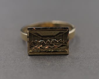 May include: A gold ring with a rectangular design featuring a depiction of the Last Supper.