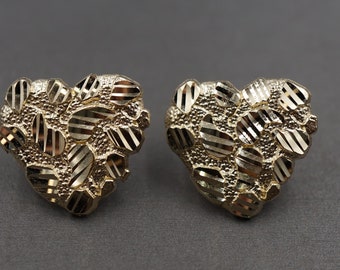 May include: A pair of gold heart-shaped earrings with a textured, diamond-cut design.