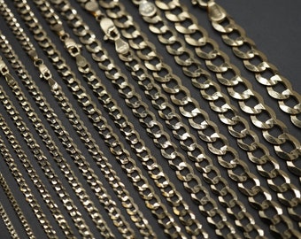 Pode incluir: Uma coleção de correntes de ouro de diferentes larguras e comprimentos, exibidas em um fundo escuro. As correntes são feitas de um material dourado brilhante e metálico e têm um design clássico de corrente curb.
