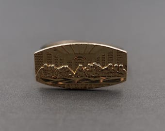 May include: A gold-colored ring with a raised design depicting the Last Supper. The ring is a religious symbol.