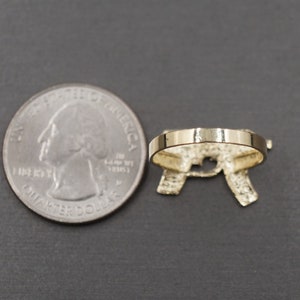 May include: A gold-tone ring with a letter 'R' design. The ring is shown next to a US quarter for size comparison.