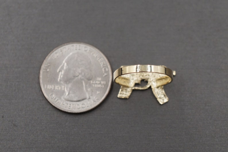 May include: A gold-tone ring with a letter 'R' design. The ring is shown next to a US quarter for size comparison.
