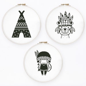 May include: Three black and white embroidery hoops with different designs. The first hoop features a teepee with geometric patterns. The second hoop features a bear wearing a headdress with feathers. The third hoop features a person wearing a headdress with feathers and holding a spear.