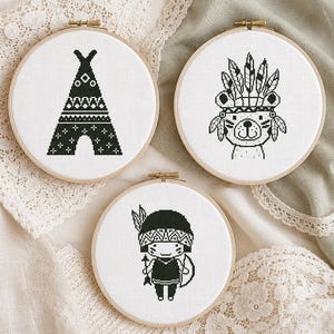 Boho nursery cross stitch pattern PDF set of 3 featuring a patterned teepee, a cute bear wearing a feather headdress, and a small child in tribal-style costume with bow and arrow, all in a bold monochrome black and white style. A striking stitching project for boho nursery crafters and adventure-themed kids' room enthusiasts. Digital instant download counted cross stitch chart.