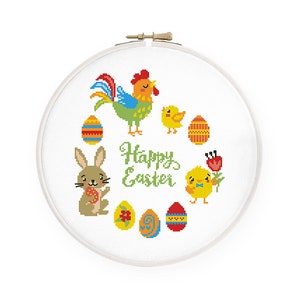 May include: A white embroidery hoop with a cross stitch design featuring a rooster, chicks, bunnies, and eggs. The text "Happy Easter" is stitched in green.