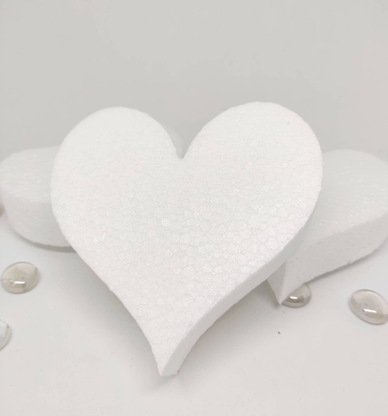 May include: Three white foam heart shapes, two are smaller and one is larger. The larger heart is in the center of the image and the two smaller hearts are on either side of it.