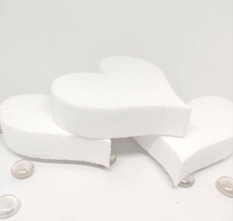 May include: Three white foam heart shapes stacked on top of each other. The hearts are smooth and have a slightly rounded edge.